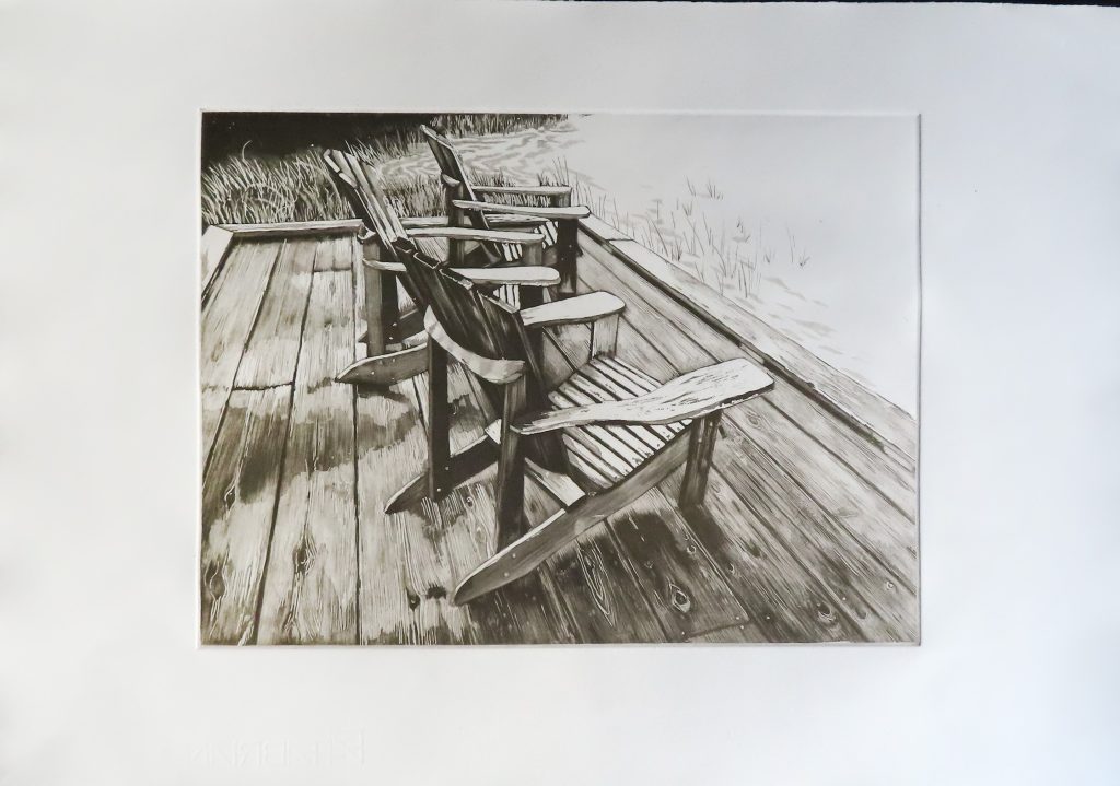 3 chaises en bois sur une terrasse tournées vers un lac